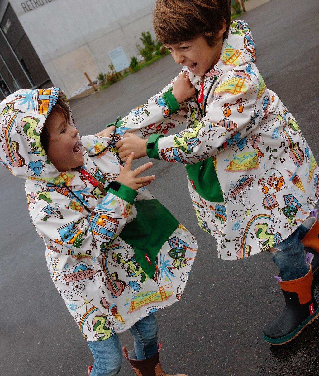 Duo d'enfants portant le poncho de pluie imperméable avec capuche San Francisco – vue de côté – Hello Hossy