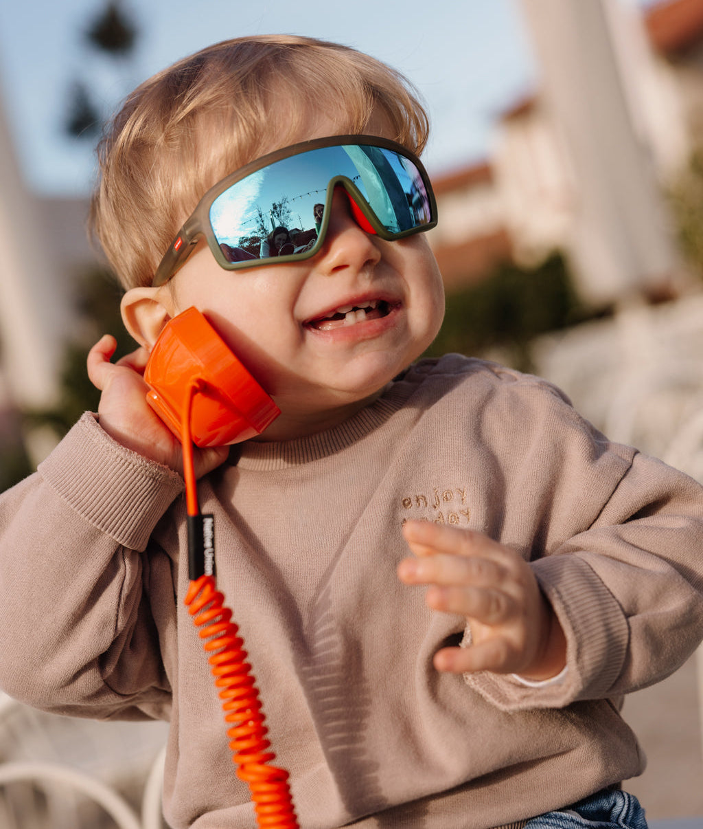 Gafas de sol infantil verde modelo deportivo espejo azul puestas por un bebé Hello Hossy