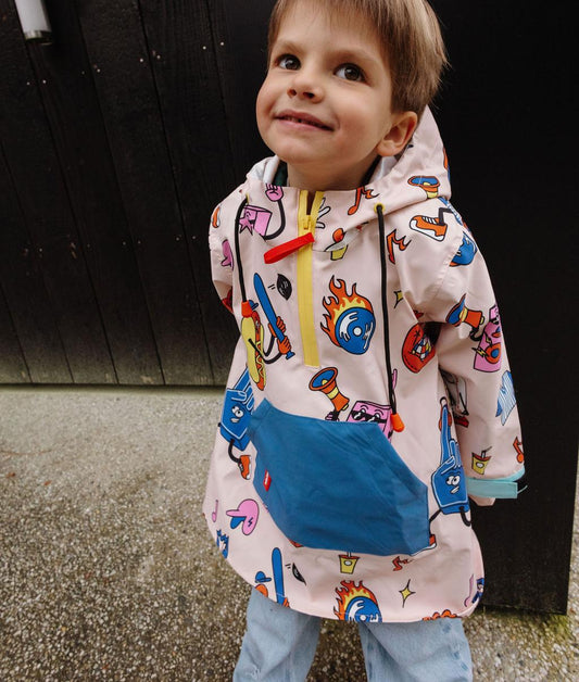 Poncho impermeable infantil crema estampado deportivo rojo y azul, bolsillo azul Hello Hossy
