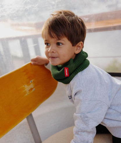 Niño con snood verde de punto acanalado y etiqueta roja Hello Hossy